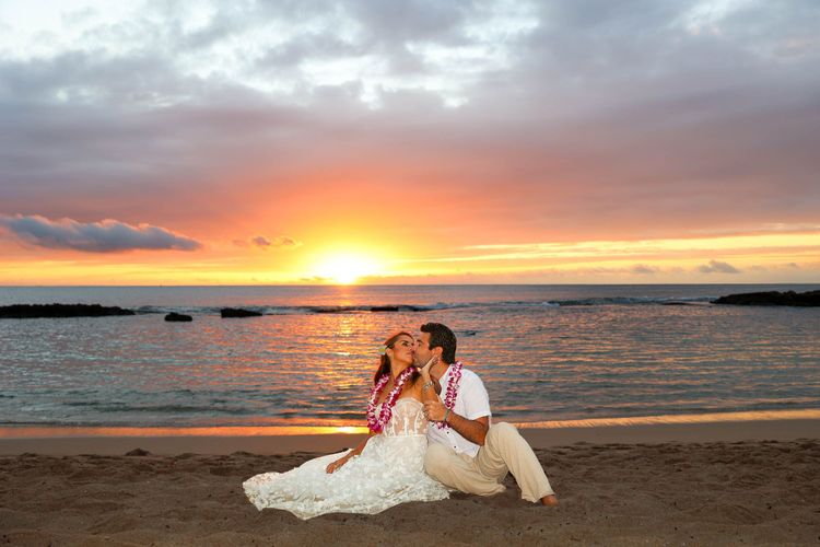 Romantic couple on Hawaii beach during vibrant orange and pink sunset