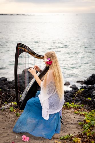 Woman playing a harp at a Hawaii beach wedding