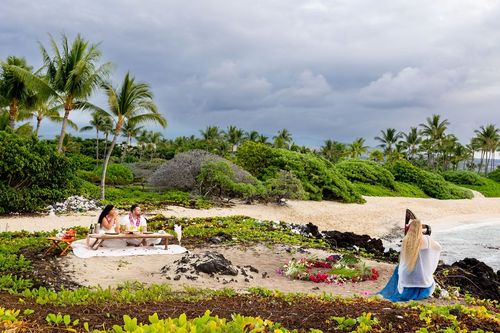 Scenic beach picnic setup under palm trees with lush tropical vegetation in Hawaii