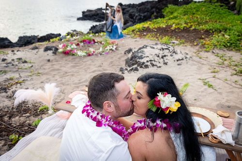 Romantic couple embracing on Hawaii beach with traditional pink flower leis and tropical setting