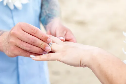 Close-up of hands exchanging wedding rings during intimate Hawaii beach ceremony