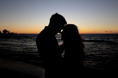 Romantic silhouette of bride and groom kissing at sunset on Hawaii beach