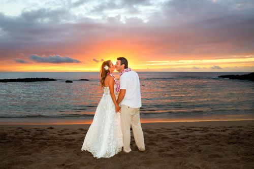Romantic bride and groom embracing on Hawaii beach during golden sunset hour