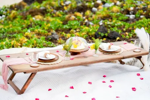 Romantic beach wedding picnic setup with lounge chairs, straw hats, and rose petals in Hawaii