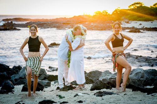 Celebrating a wedding on black lava rocks by ocean in Hawaii