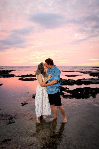 Newlywed couple standing in calm ocean waters at twilight for Hawaii wedding photos